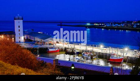 North Shields fish quay and the Low Lights lighthouse at night with local fishing boats waiting for the tide Stock Photo