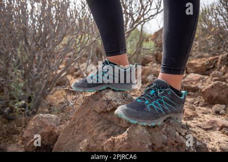 Close-up of a women's feet wearing hiking boots and standing on top of a rock. Stock Photo