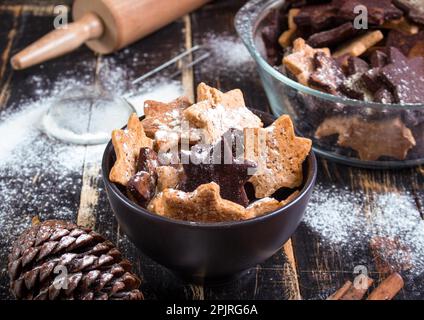 Assorted christmas ginger cookies on plate with cinnamon sticks, pinecones over dark wooden table. Six pointed star cookies Stock Photo