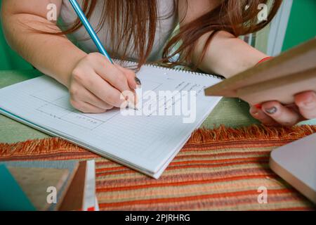 closeup unrecognizable hispanic latin woman interior designer writing on notebook with graphite pencil and holding wood swatch with hand Stock Photo