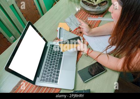 top view of young hispanic latin woman designer working at home looking at wood samples in front of the laptop, leaning on the table, making a decisio Stock Photo