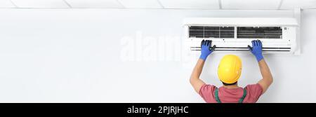 Male technician checking air conditioner indoors, space for text. Banner design Stock Photo