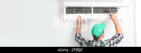 Male technician fixing modern air conditioner indoors, space for text. Banner design Stock Photo