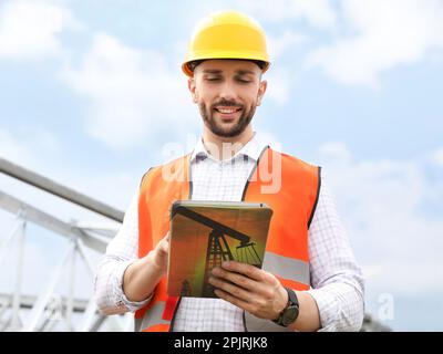 Professional engineer wearing uniform with tablet outdoors Stock Photo