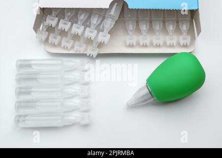 Single dose ampoules of sterile isotonic sea water solution and nasal aspirator on white background, top view Stock Photo