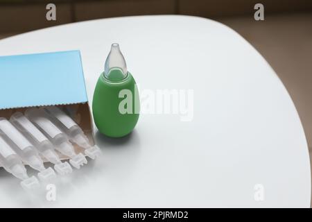 Package with single dose ampoules of sterile isotonic sea water solution and nasal aspirator on white table. Space for text Stock Photo