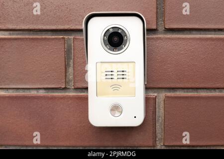 Modern intercom with camera on red brick wall Stock Photo