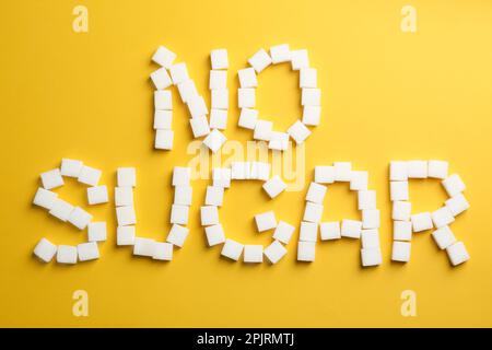 Phrase No Sugar made of refined cubes on yellow background, flat lay Stock Photo