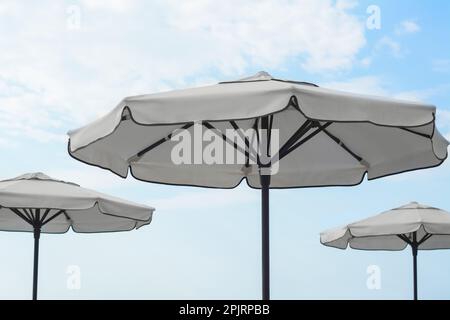 Beautiful white beach umbrellas against blue sky Stock Photo