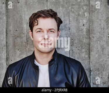 portrait of a man in jeans and a leather jacket in an urban setting Stock Photo