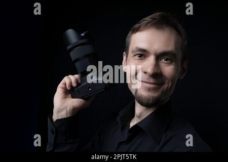 Low key portrait of a professional photographer smiling man with dslr camera Stock Photo