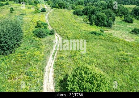 winding country road among green meadow. summer countryside landscape in sunny day. drone photo. Stock Photo