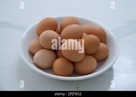 A bowl full of eggs on a white marble background Stock Photo