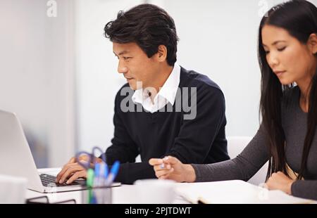 Collaborating on a project. two business professionals working together on a project. Stock Photo