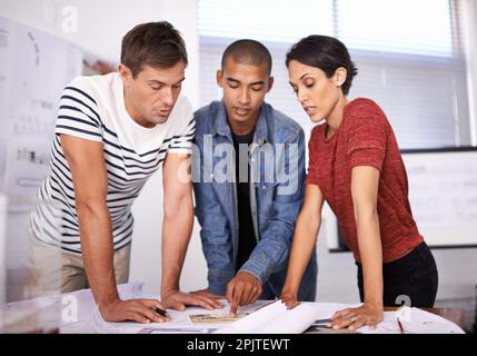 Designing with purpose. Three architects working on their blueprints together in the boardroom. Stock Photo