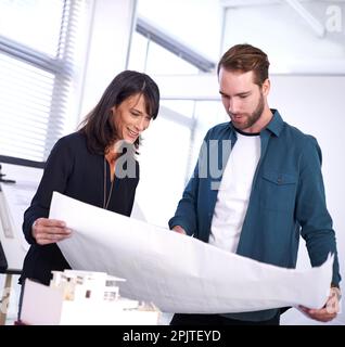 These are looking fantastic. two architects looking over some building plans in the office. Stock Photo