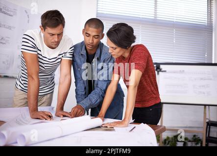 Combing through the designs to ensure quality. a group of young designers working together in an office. Stock Photo