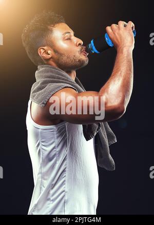 Rehydrating after an epic workout. Studio shot of a fit young man isolated on black. Stock Photo