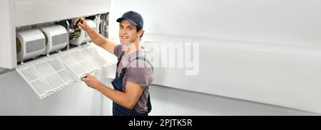Male technician repairing air conditioner indoors, space for text. Banner design Stock Photo