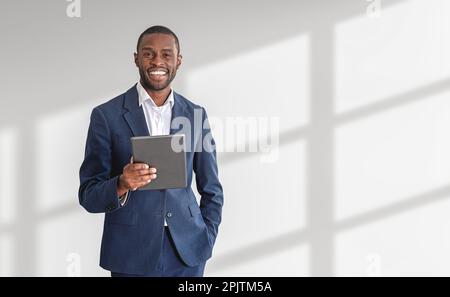 Smiling young African American businessman holding tablet computer over white background. Concept of hi tech. Mock up Stock Photo