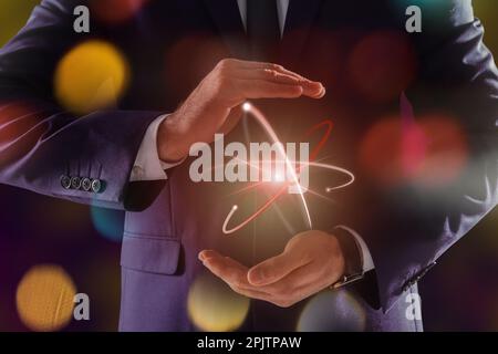Man holding virtual model of atom on color background, closeup Stock Photo