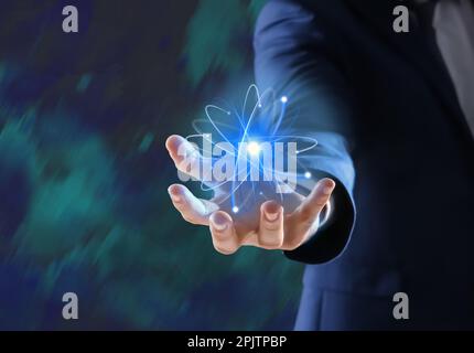 Man holding virtual model of atom on color background, closeup Stock Photo