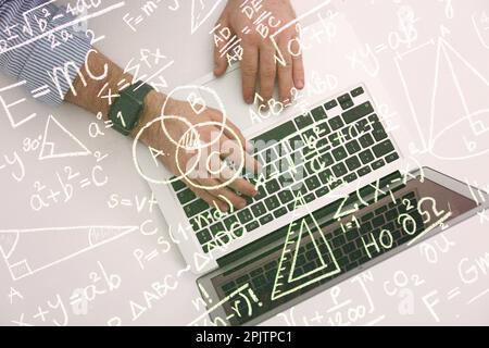 Science and education concept. Illustration of basic physics and mathematics formulas and man working on laptop at table, top view Stock Photo