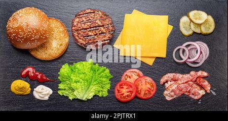 Cheeseburger or hamburger ingredients on natural stone black slate serving plate. Flat lay. Stock Photo