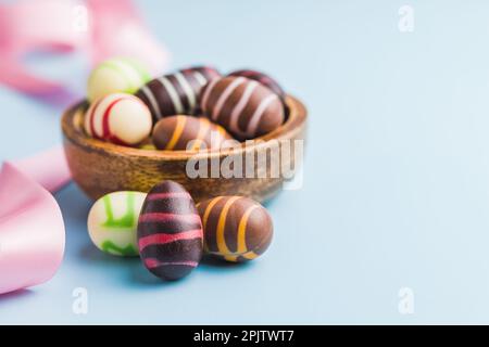 Chocolate easter eggs in bowl on the blue background. Stock Photo