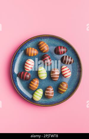 Chocolate easter eggs on plate on the pink background. Top view. Stock Photo