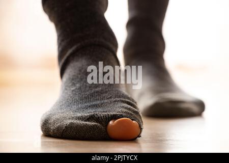 Women's feet in holey socks stand on the floor of the house, poverty, feet Stock Photo