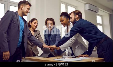 Multiracial team of happy young business people stacking hands after work meeting Stock Photo