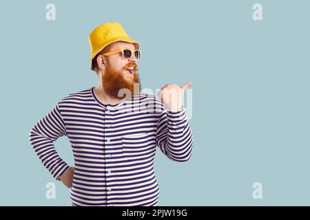 Portrait of funny red-haired happy overweight young man in striped swimming suit and yellow panama hat. Stock Photo