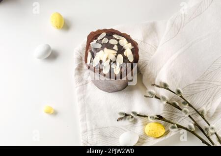 Place setting for Easter dinner on the white table with Easter cake with colorful topping, Decorative chocolate eggs sweets, willow and holiday decora Stock Photo