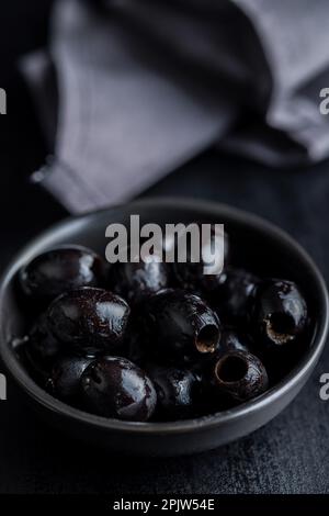 Pitted black olives in bowl on the kitchen table. Stock Photo