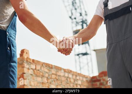 Doing handshake. Two construction workers is together at the building Stock Photo