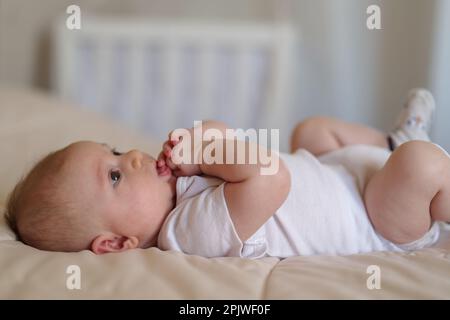 A 3 month old baby boy laying on a bed Stock Photo