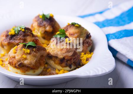 Eggs stuffed with tuna with béchamel au gratin in the oven. Stock Photo