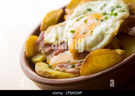 Fried eggs with chips and serrano ham. Traditional Spanish tapa nicknamed Huevos Rotos. Stock Photo