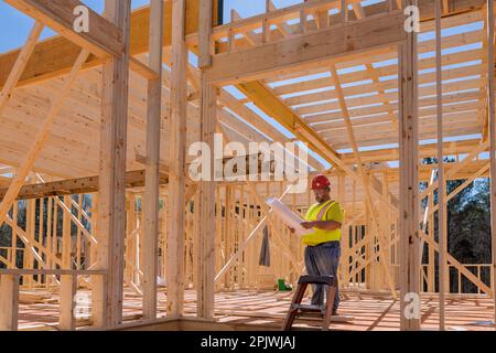 An engineer checking quality of wooden frame using blueprint plan architecture during construction phase project Stock Photo