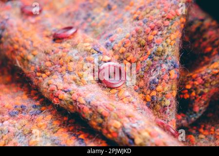 Knitted warm colorful sweater with orange buttons. Cozy composition in the home atmosphere, warm colors. Wool fabric texture close up background. Comf Stock Photo