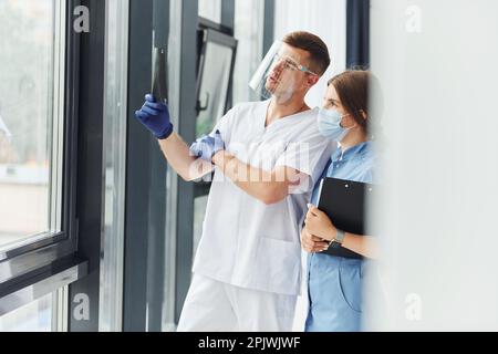 Looking at documents. Two doctors in uniform standing indoors and working together Stock Photo