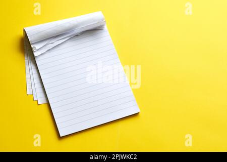 Top view of blank open notebook with torn pages. Page with lines on yellow background with copy space. For use as mock up or template. Stock Photo