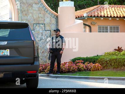 Armed Secret Service agent guards the entrance to Mar-a-Lago.Former President Donald Trump arrives at Palm Beach International Airport as supporters w Stock Photo