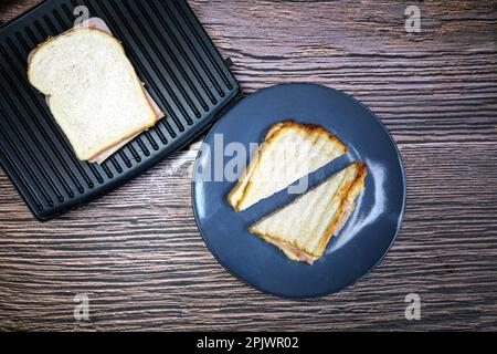 Modern grill maker with Grilled cheese sandwich on wooden table top view copy space Stock Photo