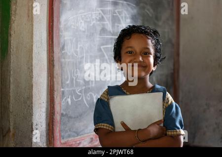School girl holding book standing at school Stock Photo - Alamy