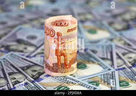 Russian rubles rolled up on background of US dollars. Concept of exchange rate, sanctions Stock Photo