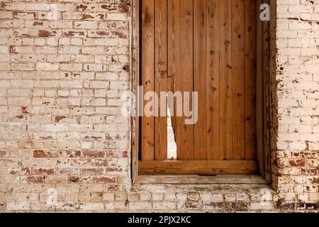 Shuttered window with break in shutter and old white washed brick wall. Stock Photo
