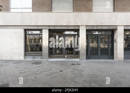 Exterior portal to the street of a simple residential building with painted metal doors and golden details Stock Photo