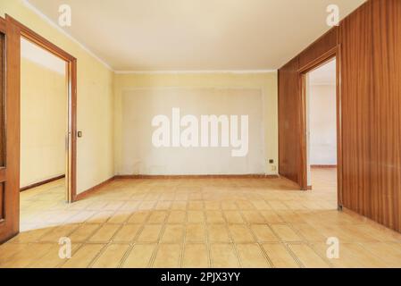 Living room of an empty house with walls covered in varnished sapele wood panels and light brown stoneware floors Stock Photo